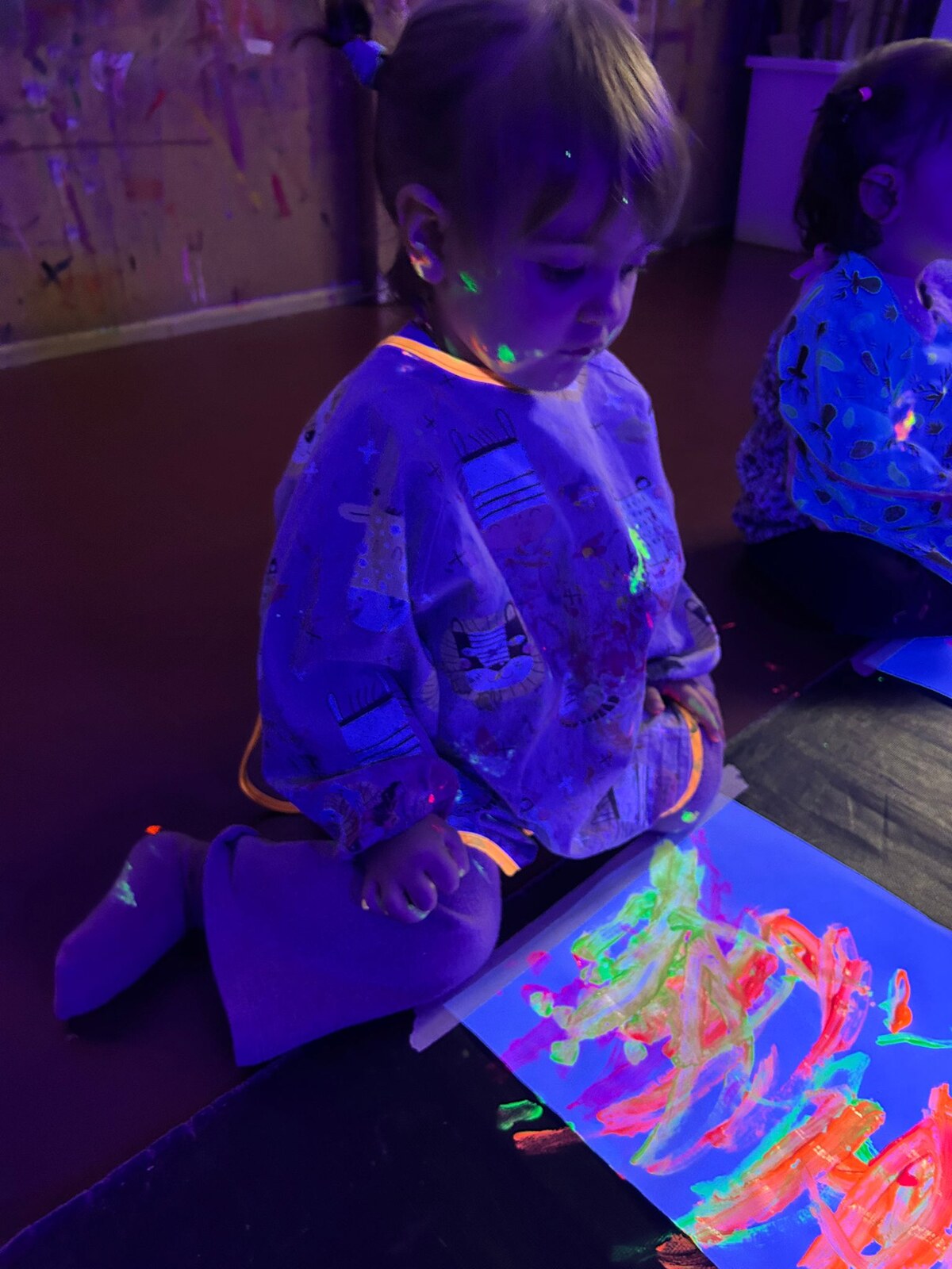 Bambina dipinge con colori fluorescenti durante un atelier fluo Tomorò